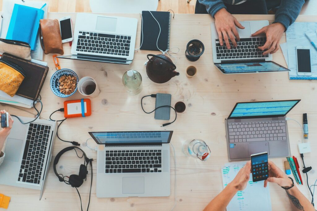 Team di lavoro con laptop e documenti su tavolo condiviso
